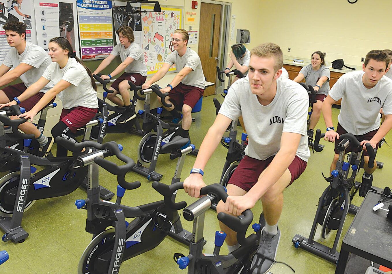 A group of people riding stationary bikes in a gym.