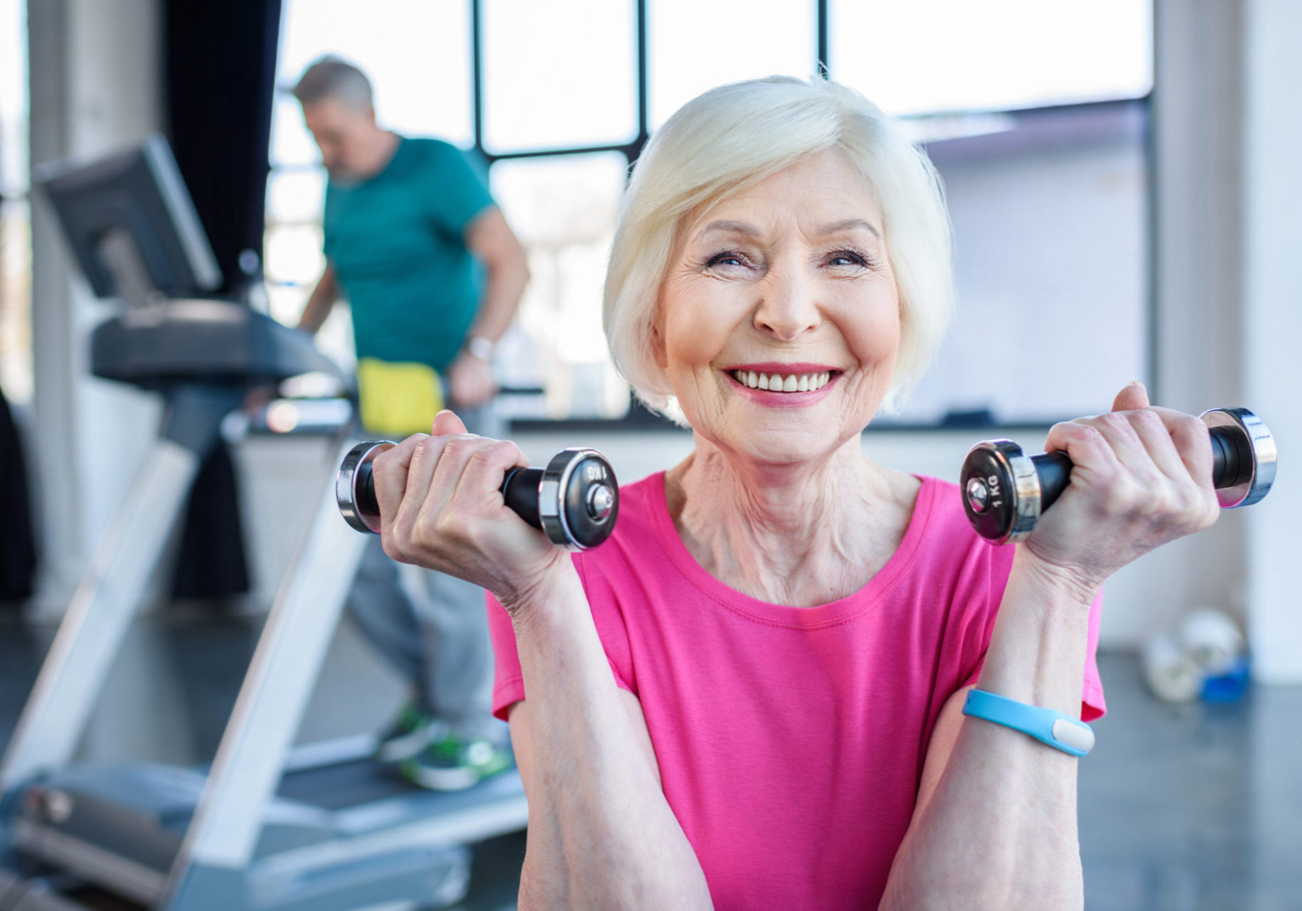 A woman is holding two dumbbells in her hands.