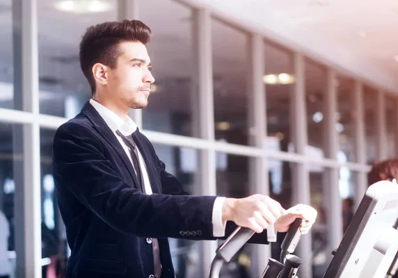 A man in suit and tie riding an exercise bike.